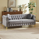 82-Inch Velvet Chesterfield sofa with two round pillows, featuring copper stud detailing and tufted button accents, with metal legs. Loop design allows for hanging cartoon ornaments.